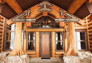 Custom designed timber frame entrance truss with cedar flare posts on a log home by Log and Timber Works British Columbia