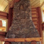 Log mantel and plinths above a fireplace in a log home by Log and Timber Works Saskatchewan