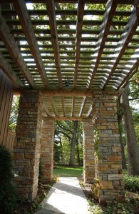 Custom designed log and timber frame trellis with stone posts by Log and Timber Works Saskatchewan