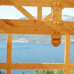 Lake view through the timbers of a custom designed timber frame home under construction by Log and Timber Works Saskatchewan