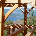Lake view through the timbers of a custom designed timber frame home under construction by Log and Timber Works Saskatchewan